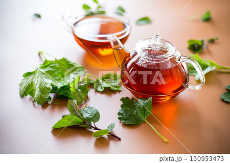 Natural tea from currant leaves and mint on brown background Natural tea from currant leaves and mint on brown background 130953473