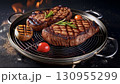Grilled beef steaks with rosemary, salt, and pepper on wooden board. Juicy barbecue meat with spices. Delicious cooked beef fillet on dark rustic background. 130955299