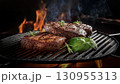 Grilled beef steaks with rosemary, salt, and pepper on wooden board. Juicy barbecue meat with spices. Delicious cooked beef fillet on dark rustic background. 130955313
