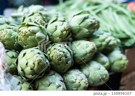 Pile of fresh artichokes laid out on counter of greengrocer shop closeup Pile of fresh artichokes laid out on counter of greengrocer shop closeup 130956107