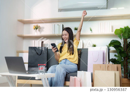 Celebrating Online Shopping Success. Woman cheering with phone after purchase. 130956387