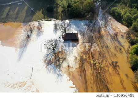 Aerial view of sinking village house in the middle of toxic mine decanting lake 130956489