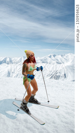Female skier in bikini standing with poles on snowy mountain with confident smile. Hand made collage 130956628