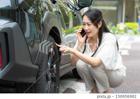 車を確認する女性　タイヤ　スマホ 130956902