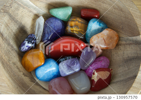 Different precious gem stones inside a wooden bowl 130957570