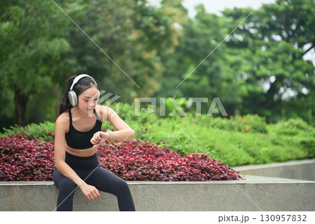 Female athlete taking a break during workout, monitoring fitness data on smartwatch Female athlete taking a break during workout, monitoring fitness data on smartwatch 130957832