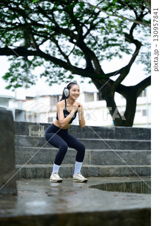 Smiling athlete training legs with squat exercise during outdoor cardio session 130957841