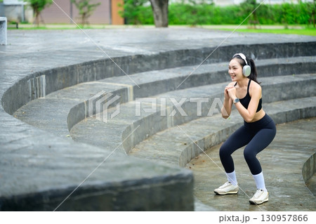 Asian woman in sportswear practicing fitness workout on stone steps in an urban outdoor space 130957866