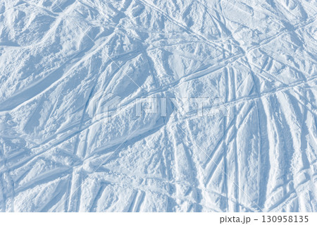Snowy abstract off-piste skiing background with ski and snowboard trails and tracks on new virgin powder snow. morning sunrise or evening sunset time at alpine mountain resort 130958135