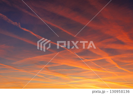 Scenic dramatic colorful sunset or sunrise sky landscape many aircraft jet contrail crossing. Natural beautiful dawn background wallpaper. Twilight time cloudscape. Europe aircraft traffic 130958136