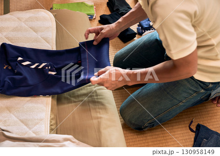 畳に座って洗濯物をたたむ男性の連続写真。家事をする男性。 130958149