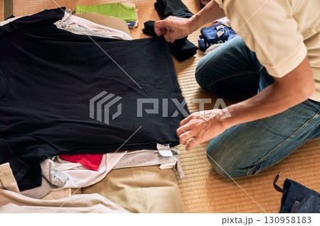 畳に座って洗濯物をたたむ男性の連続写真。家事をする男性。 130958183