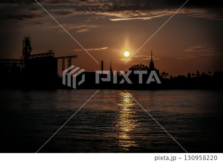 Gorgeous scenic of Thai temple silhouettes and Industrial factory along Chao phraya river over sun at sunrise. 130958220