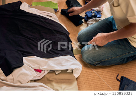 畳に座って洗濯物をたたむ男性の連続写真。家事をする男性。 130959325