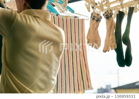 洗濯物を取り入れる男性の連続写真。家事をする男性。 130959331