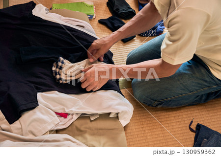 畳に座って洗濯物をたたむ男性の連続写真。家事をする男性。 130959362