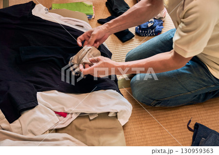 畳に座って洗濯物をたたむ男性の連続写真。家事をする男性。 130959363
