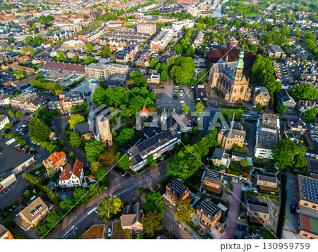 A European town with a tall green-spired church at its center, surrounded by houses, gardens, and winding streets, blending historic architecture with lush green spaces. A European town with a tall green-spired church at its center, surrounded by houses, gardens, and winding streets, blending historic architecture with lush green spaces. 130959759