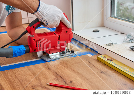 repairman using electric jigsaw and cutting hole for the sink in the kitchen countertops repairman using electric jigsaw and cutting hole for the sink in the kitchen countertops 130959898