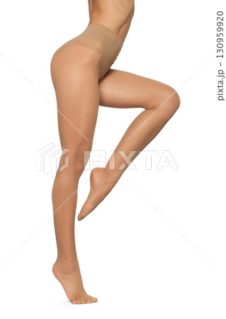 Beautiful long fit female legs in beige tights on white background 130959920