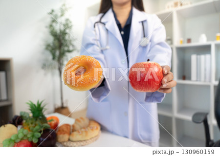 Healthy Choices: Doctor Presenting Apple and Donut to Patient Healthy Choices: Doctor Presenting Apple and Donut to Patient 130960159