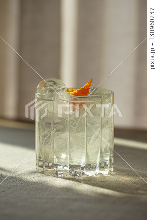 Gin and tonic cocktail with ice in faceted glass Gin and tonic cocktail with ice in faceted glass 130960237
