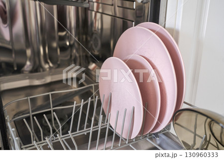 Pink plates in open dishwasher with stainless steel interior Pink plates in open dishwasher with stainless steel interior 130960333