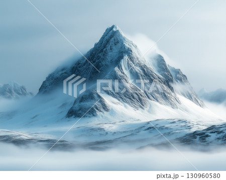 Majestic snow-covered mountain peak rising through fog in a cold winter landscape 130960580