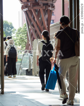 夏の金沢駅東もてなしドーム広場を渡る通勤中の女性会社員の姿 130960829