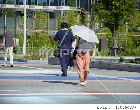 夏の朝の金沢駅西広場を渡る通勤中の会社員の姿 夏の朝の金沢駅西広場を渡る通勤中の会社員の姿 130960837
