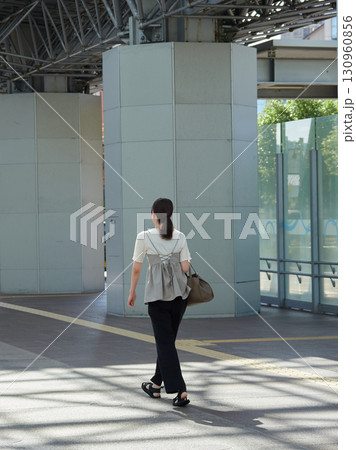 夏の朝の金沢駅東もてなしドーム広場を渡る若い女性会社員の姿 夏の朝の金沢駅東もてなしドーム広場を渡る若い女性会社員の姿 130960856