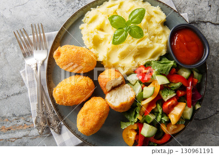 Spanish Croquettes chicken in a creamy bechamel sauce served with mashed potatoes, fresh salad and tomato sauce close-up in a plate. Horizontal top view Spanish Croquettes chicken in a creamy bechamel sauce served with mashed potatoes, fresh salad and tomato sauce close-up in a plate. Horizontal top view 130961191