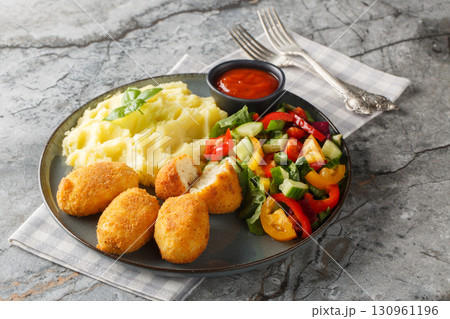 Hot chicken bechamel croquettes with mashed potatoes, vegetable salad and ketchup close-up in a plate. Horizontal Hot chicken bechamel croquettes with mashed potatoes, vegetable salad and ketchup close-up in a plate. Horizontal 130961196