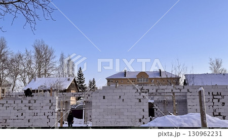 A snowy construction site is showcased, with partially constructed walls set against a clear, vibrant blue sky 130962231