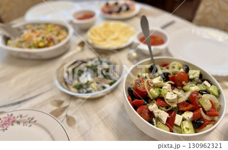 A beautifully arranged and presented table showcasing a delightful variety of fresh, colorful salads and garnishes 130962321