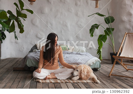 Mindful woman practicing yoga with her golden retriever in a cozy hotel room 130962392