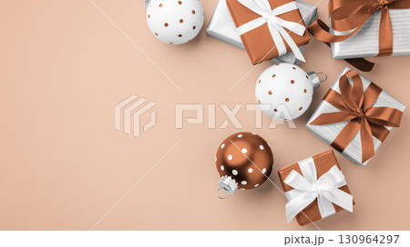 Gift boxes, present with brown bow ribbon and christmas ball decor on light brown background Gift boxes, present with brown bow ribbon and christmas ball decor on light brown background 130964297