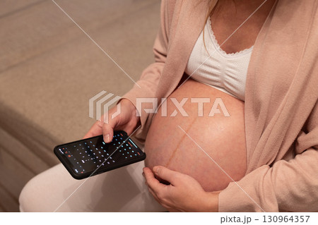 Pregnant woman looking at calendar in her phone. Baby birth date concept. 130964357