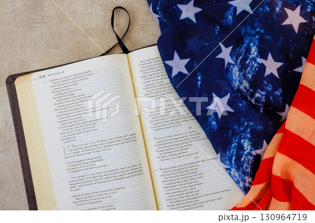 Bible opened next to patriotic American flag, symbolizing faith national pride during quiet reading session Bible opened next to patriotic American flag, symbolizing faith national pride during quiet reading session 130964719