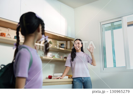 Back to School. Young girl waving goodbye to her mother before school. 130965279