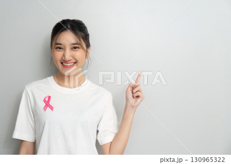 Breast Cancer Awareness. Young woman pointing to pink ribbon on her shirt. Breast Cancer Awareness. Young woman pointing to pink ribbon on her shirt. 130965322
