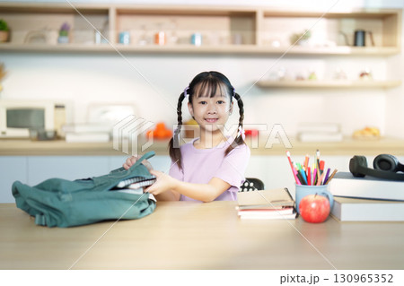 Back to School. Cheerful girl packing her backpack with school supplies. 130965352