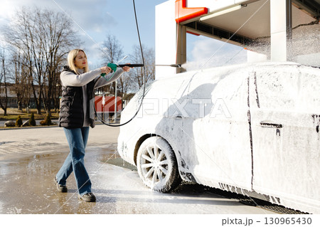 Woman washing her car with high pressure washer at self-service car wash 130965430
