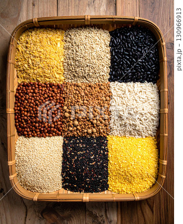 A collection of dried seeds and grains are laid out on a traditional woven tray. 130966913