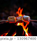 Marshmallows roasting over a campfire in the evening glow Generative AI 130967400