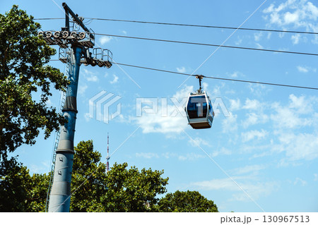 Cable car gliding through a clear blue sky over a scenic landscape during a bright summer day Cable car gliding through a clear blue sky over a scenic landscape during a bright summer day 130967513