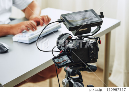 Filming a tutorial at a modern workspace with advanced camera setup and keyboard use 130967537