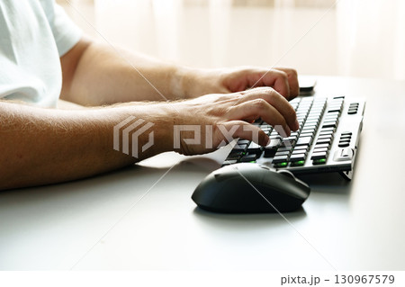 Person typing on a keyboard with a mouse beside on a minimal workspace desk 130967579