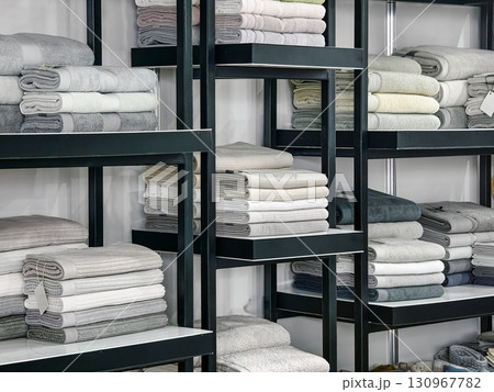 Soft and neatly folded towels displayed on shelves in a modern setting during daytime Soft and neatly folded towels displayed on shelves in a modern setting during daytime 130967782