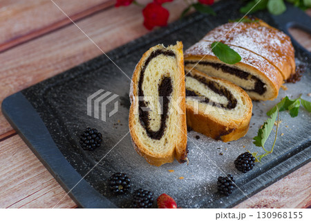Homemade poppy seed roll with powdered sugar on a tray Homemade poppy seed roll with powdered sugar on a tray 130968155